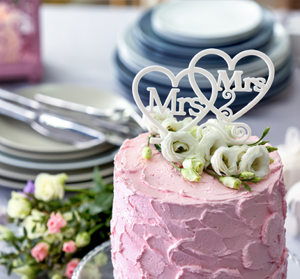 一个粉红色的结婚蛋糕，上面有太太和太太。